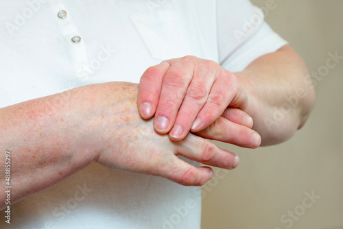 An elderly woman suffering from pain in her fingers close-up. An elderly lady touches her hand, joint pain, joint problems. An elderly woman is holding her sore hand.