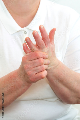 An elderly woman suffering from pain in her fingers close-up. An elderly lady touches her hand, joint pain, joint problems. An elderly woman is holding her sore hand.