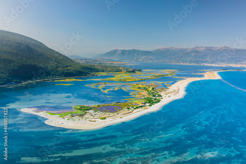 Aerial view of the sandbank separating shoal and blue lagoon against backdrop of mountains, near island of Lefkada, summer Greece