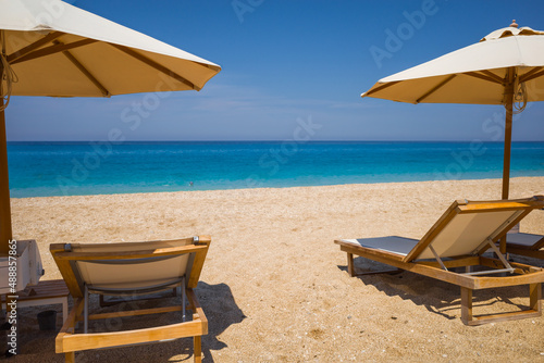 Passage to turquoise sea between sun loungers and sun umbrellas. Holidays on islands of Greece