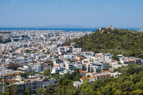 Snow-white houses of Greek capital, green hills against background of sea. Athens, Greece