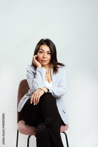 Full length portrait of smiling attractive businesswoman in suit posing while standing with arms crossed and looking at camera isolated over white background