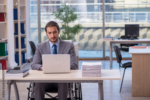 Young male employee in wheel-chair working in the office