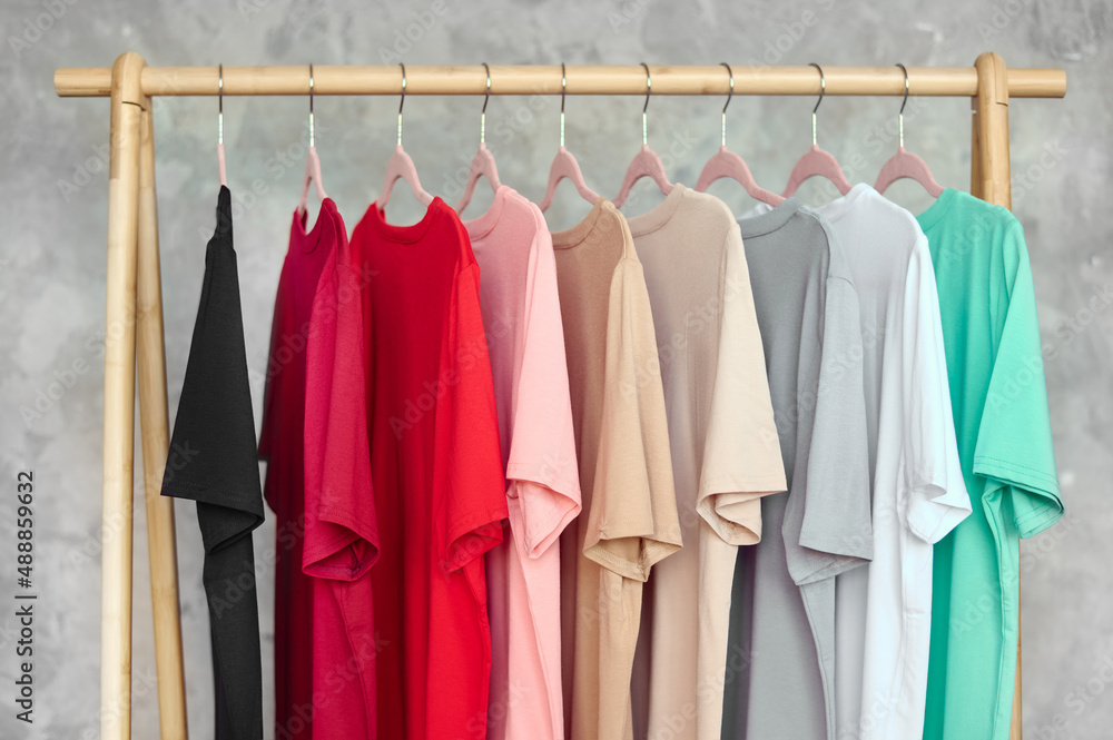 Fashion clothes on clothing rack - bright colorful closet. Closeup of rainbow color choice of trendy female wear on hangers in store closet or spring cleaning concept. Summer home wardrobe.