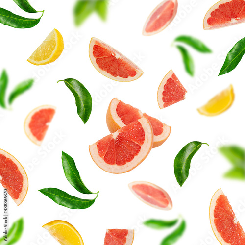 Background of sliced ​​grapefruit and green leaves on a white background.