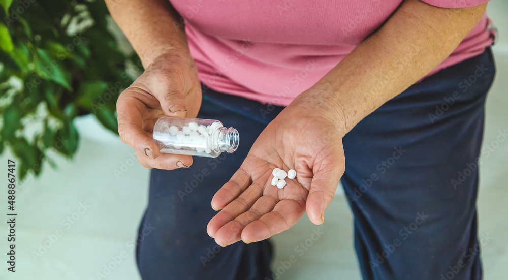 An old woman holds pills in her hands. Selective focus.