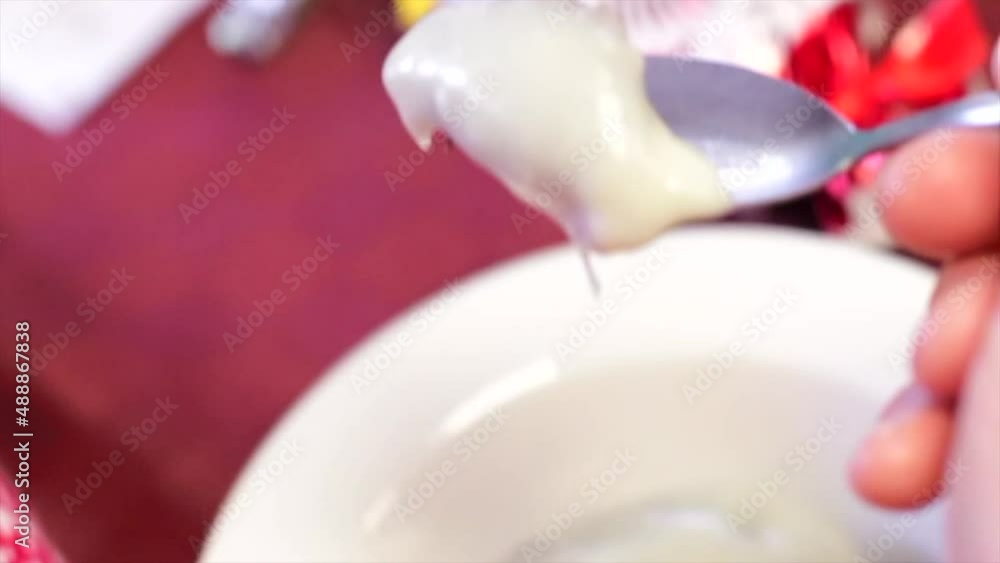 Taking a spoonful and eating Christmas pudding with brandy custard sauce in white bowl slow motion Taking a spoonful and eating Christmas pudding with brandy custard sauce in white bowl slow motion