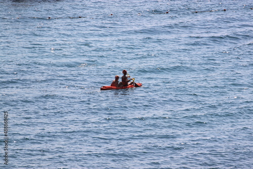 two people on a kayak are sailing on the sea on a hot summer day