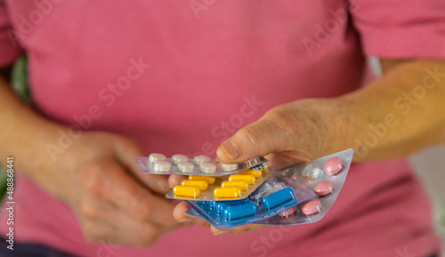 An old woman holds pills in her hands. Selective focus.