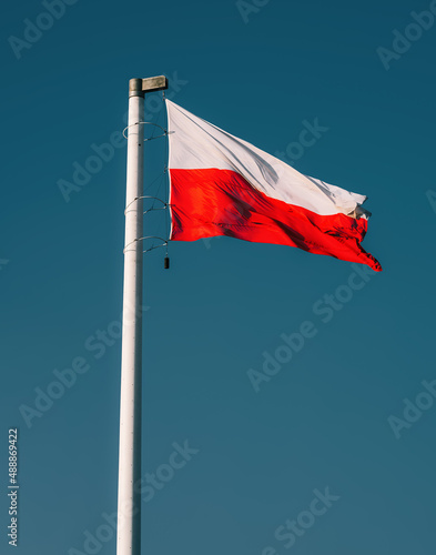 Polish flag waving in the sky. Waving national flag of Poland on a flagpole, national colors of Poland.