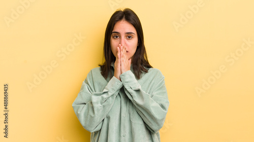 Foto young hispanic woman feeling worried, upset and scared, covering mouth with hand