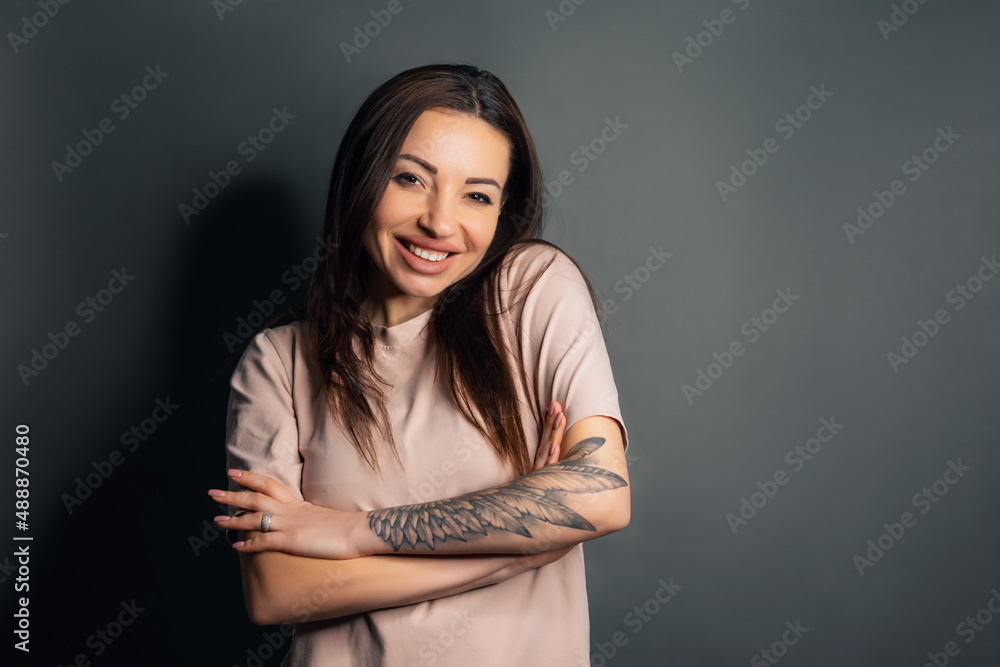 Close up shot of beautiful young redhead woman in gray T-shirt looking with cute smile at the camera while posing isolated against white concrete wall background. Human face expressions and emotions Close up shot of beautiful young redhead woman in gray T-shirt looking with cute smile at the camera while posing isolated against white concrete wall background. Human face expressions and emotions