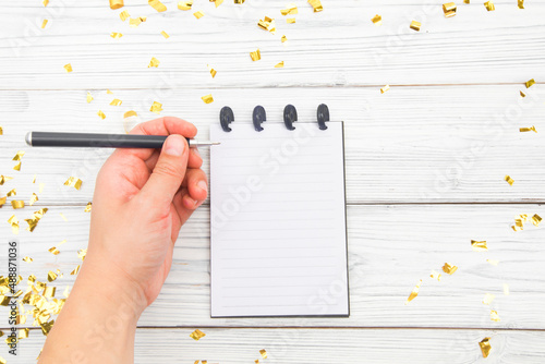 Festivedecorations and notebook with wish list on white rustic table, flat lay style. Planning concept.- Image photo