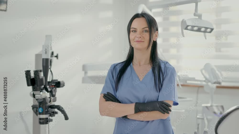 Young Female Dentist Standing In Office. She Is In Medical Gloves. Pretty Woman. Young Female Dentist Standing In Office. She Is In Medical Gloves. Pretty Woman.