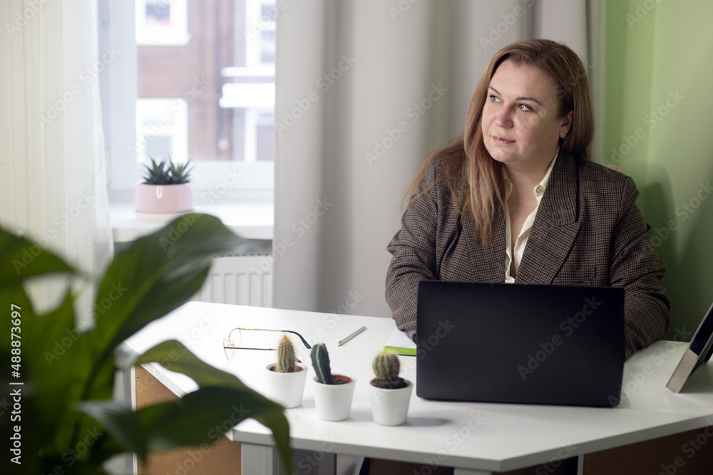 Middle aged confident woman working from home in quarantine. Female business portrait with laptop. Woman is sitting at home working remotely. Online. Business professional Middle aged confident woman working from home in quarantine. Female business portrait with laptop. Woman is sitting at home working remotely. Online. Business professional