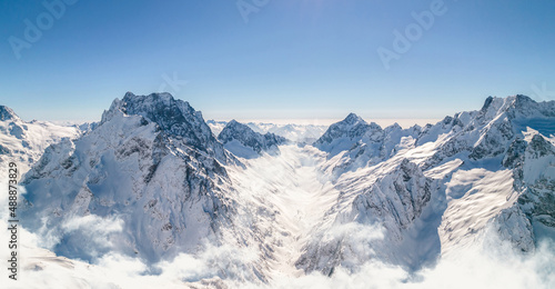 Mountain peaks shine under the sun above the clouds 