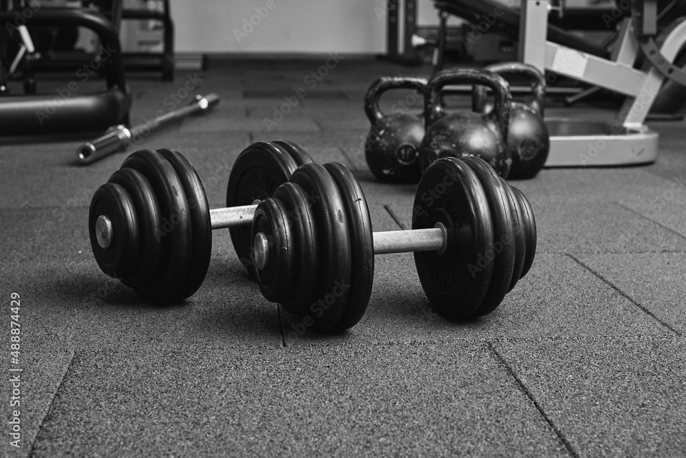 Dumbbells and kettlebells on a floor. Bodybuilding equipment. Fitness or bodybuilding concept background. black and white photography