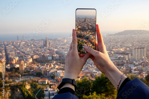 Travel concept - tourist taking a photo of Barcelona skyline on a mobile phone photo