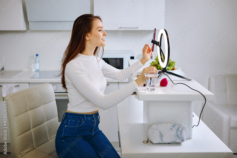 Beauty blogger uses ring light with cell phone holder during live stream at home. Beauty blogger uses ring light with cell phone holder during live stream at home.