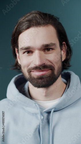 Carefree attractive guy with dark hair and beard sincerely smiling
