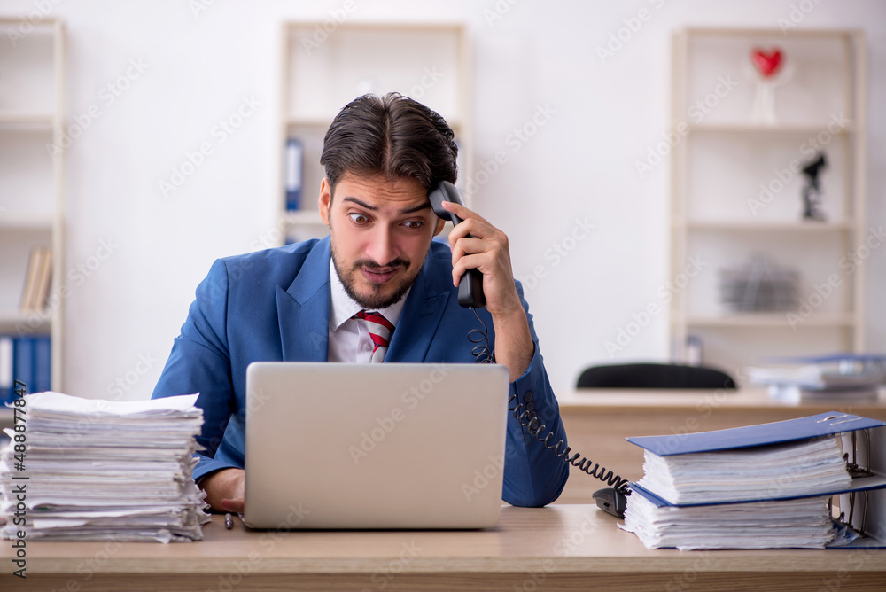 Young male employee and too much work in the office Young male employee and too much work in the office
