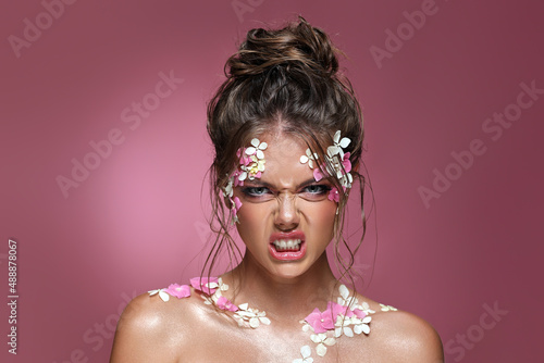 Beautiful caucasian woman with flowers on pink background.