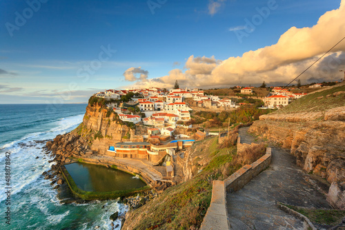 Picturesque village Azenhas do Mar. Holiday white houses on the edge of a cliff with a beach and swimming pool below. Landmark near Lisbon, Portugal, Europe. Landscape at sunset. photo
