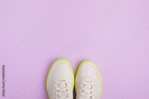 beige neon-soled sneakers on color background - Image
