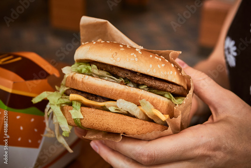 Burger in hand. Big tasty burger in girl hand