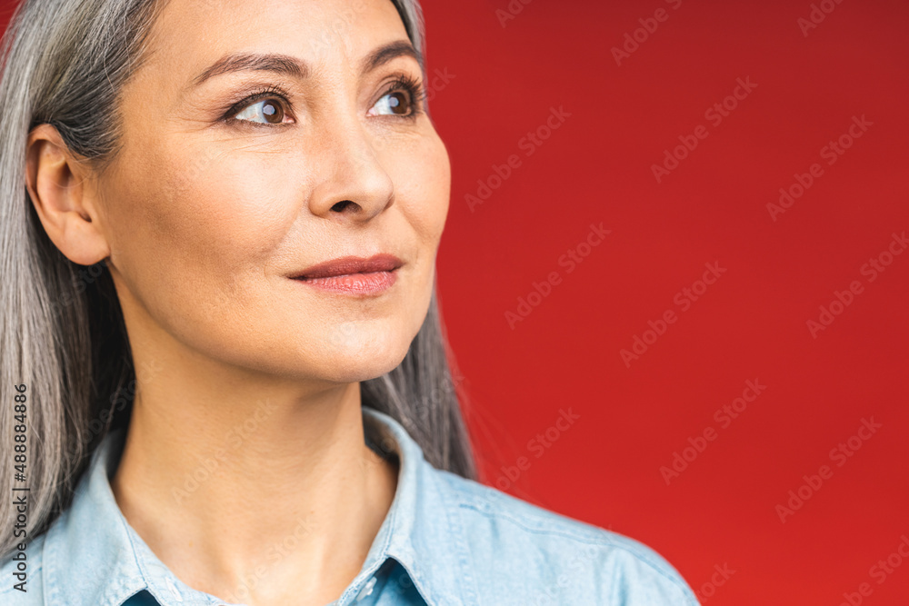 Happy elegant mature senior aged business woman smiling standing isolated over red background. Smiling confident cheerful middle aged lady, copy space.