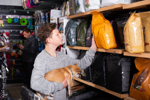 Customer teenager with dog chihuahua choosing dry food in petstore photo