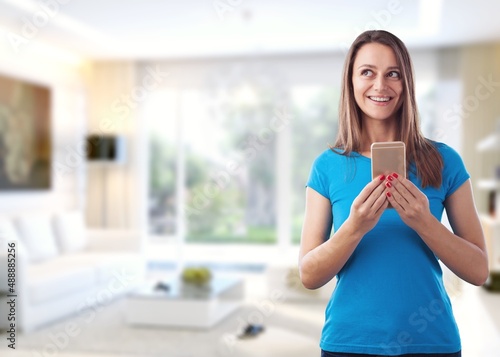 Young smiling cheerful woman hold in hand using mobile cell phone chatting browsing