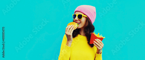 Foto Portrait of stylish happy smiling young woman eating a burger and french fries f