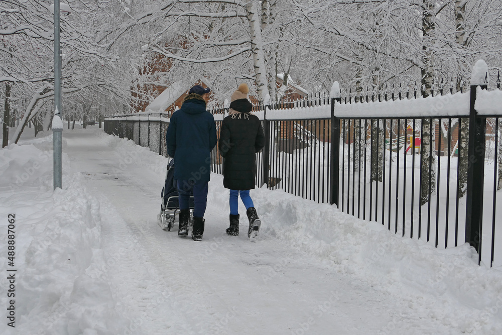 People, a young family park walk in the park in winter, snowfall in the park. High quality photo