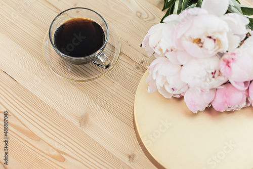 Styled composition with pink tulips and cup coffee on gold background. Flat lay floral frame and white textile. Border top view.