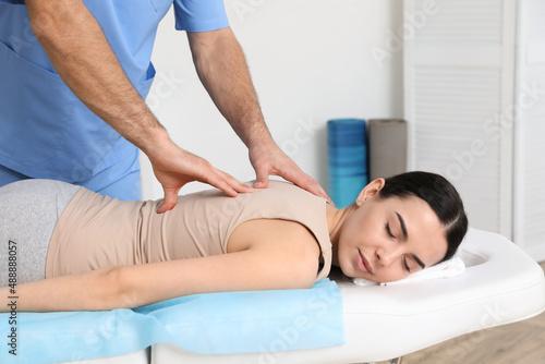 Orthopedist massaging young woman's back in clinic, closeup. Scoliosis treatment