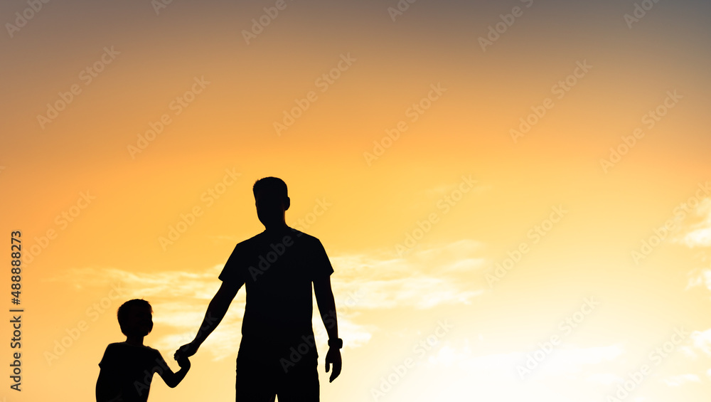 Silhouette of father and son walking holding hands 