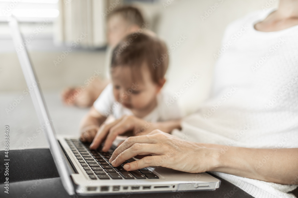 Mother working on laptop and watching kids at home Mother working on laptop and watching kids at home