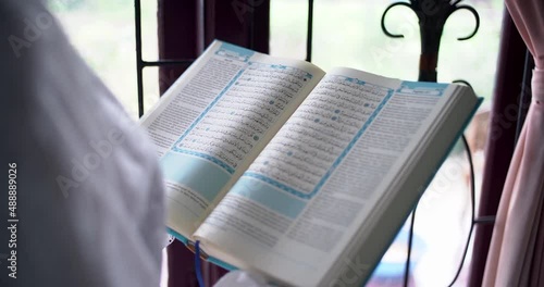 woman reading the quran behind the window photo