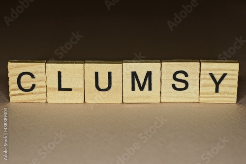 gray word clumsy made of wooden letters on brown background
