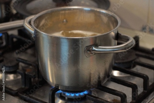 one gray open metal pan stands on the blue fire of a gas stove in the kitchen