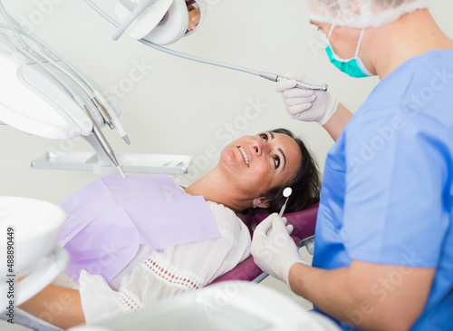 dentist professional filling teeth woman patient sitting in medical chair