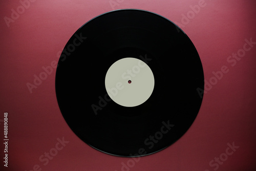 Classic vinyl record close-up on a red burgundy background  outdated data storage  music