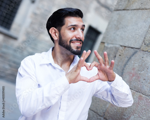 Cuadro en lienzo Handsome passionate man making heart with finger outdoors