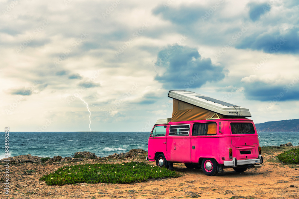 pink clasic camper van standing in front of the sea on a cliff with dramatic sky - travel concept. pink clasic camper van standing in front of the sea on a cliff with dramatic sky - travel concept.