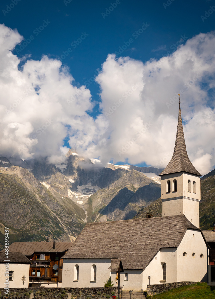 The church of the Swiss town Bellwald in the canton of Valais, with mountains and impressive cloud formations in the background