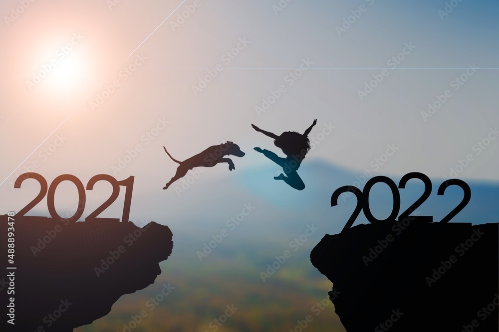 Dog jumping with owner to new year 2022 at top of mountain with sunset. Dog jumping with owner to new year 2022 at top of mountain with sunset.