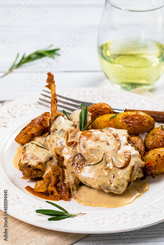 Rabbit Meat With Rosemary in Sour Cream Sauce and Potato on White Wooden Background. Selective focus.