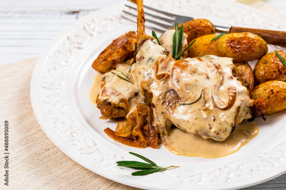 Rabbit Meat With Rosemary in Sour Cream Sauce and Potato on White Wooden Background. Selective focus.