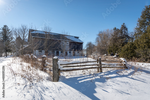 An old farmhouse is seen in the winter surrounded by snow. © EricLysenko